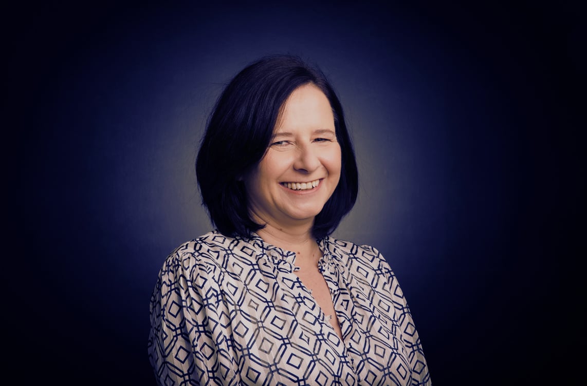 A picture of Claire smiling in a blue and white patterned shirt